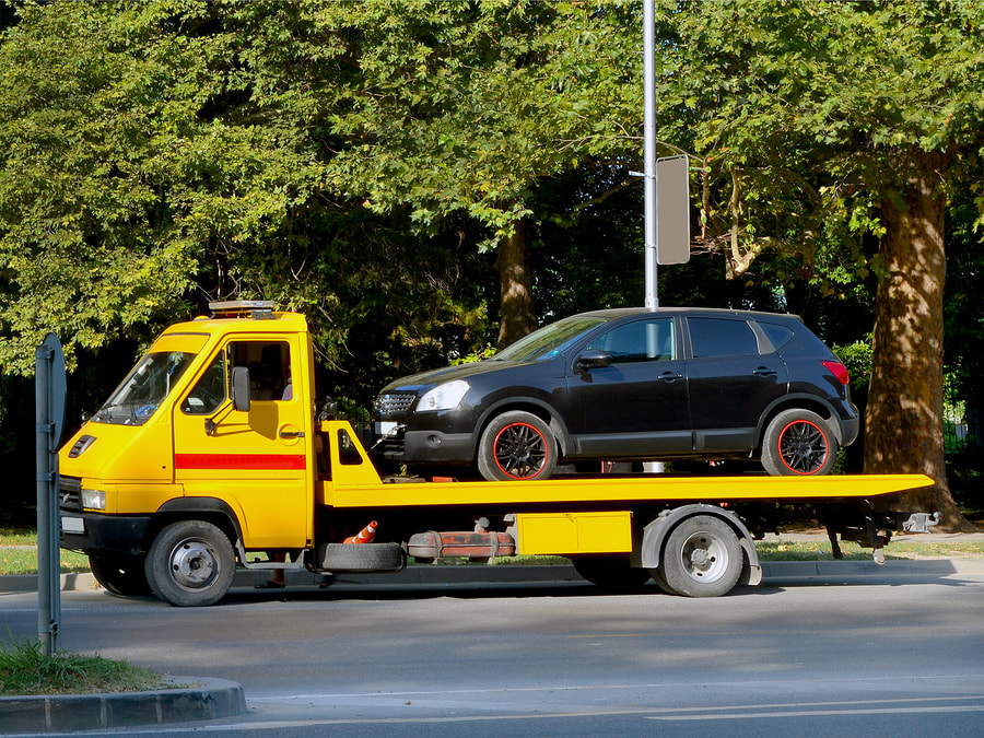 black car on the yellow towing truck